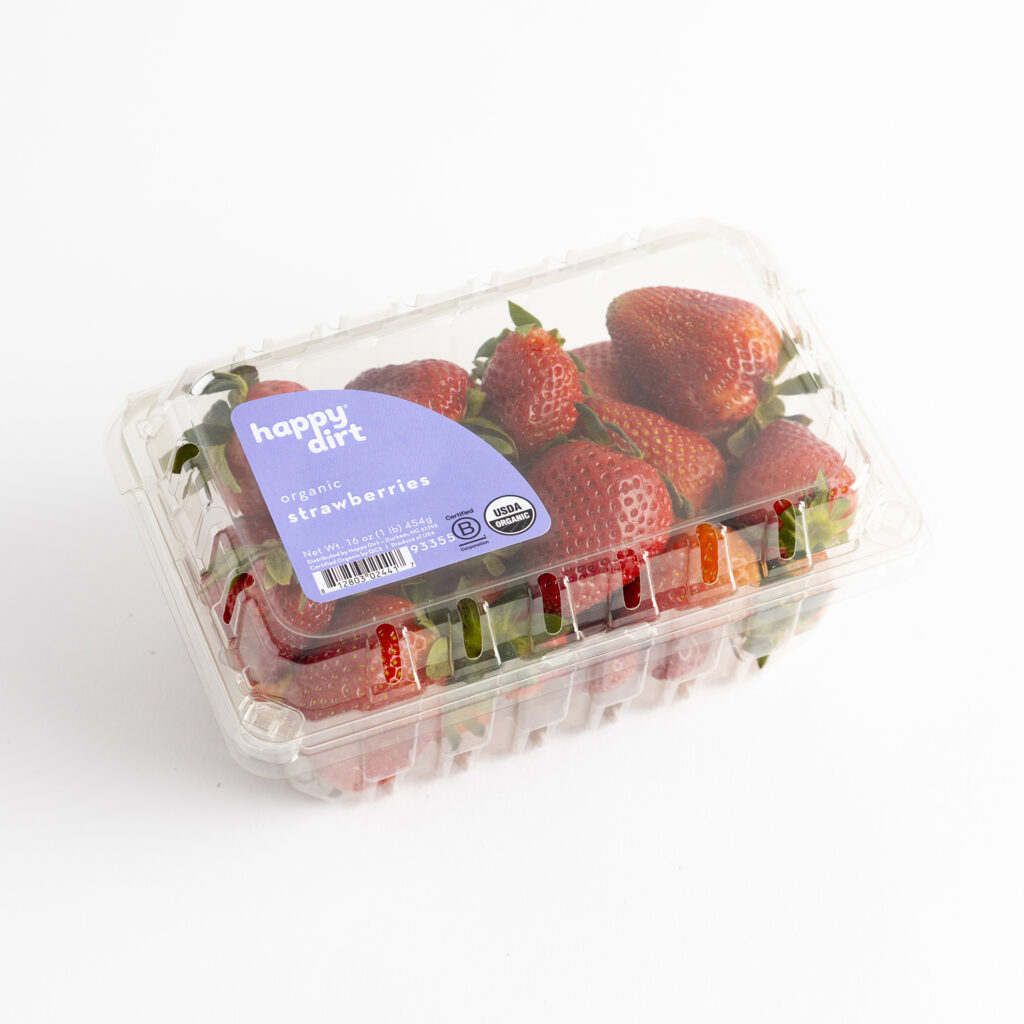clamshell of organic strawberries on a white surface