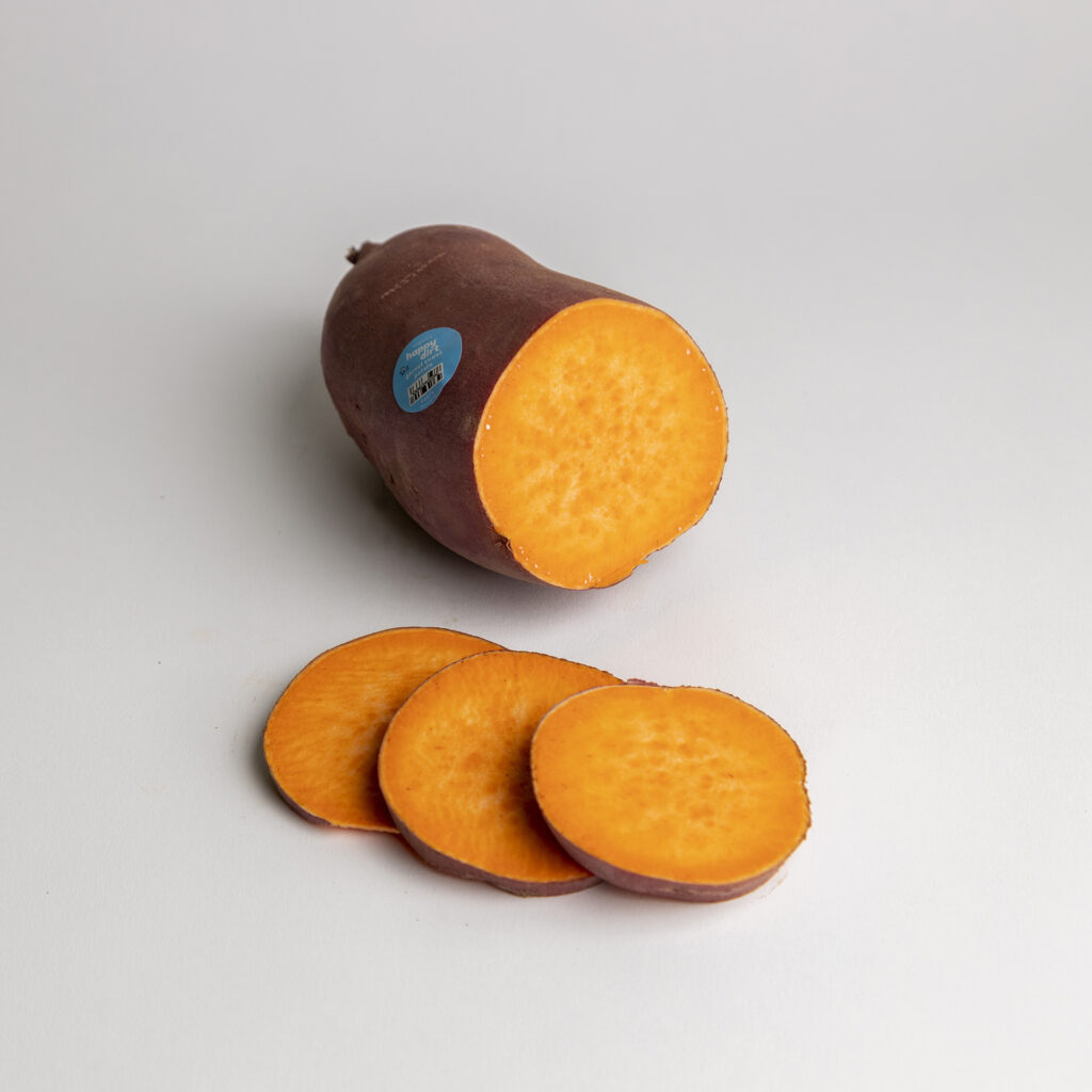a sliced organic garnet sweet potato on a white backdrop with a blue happy dirt sticker