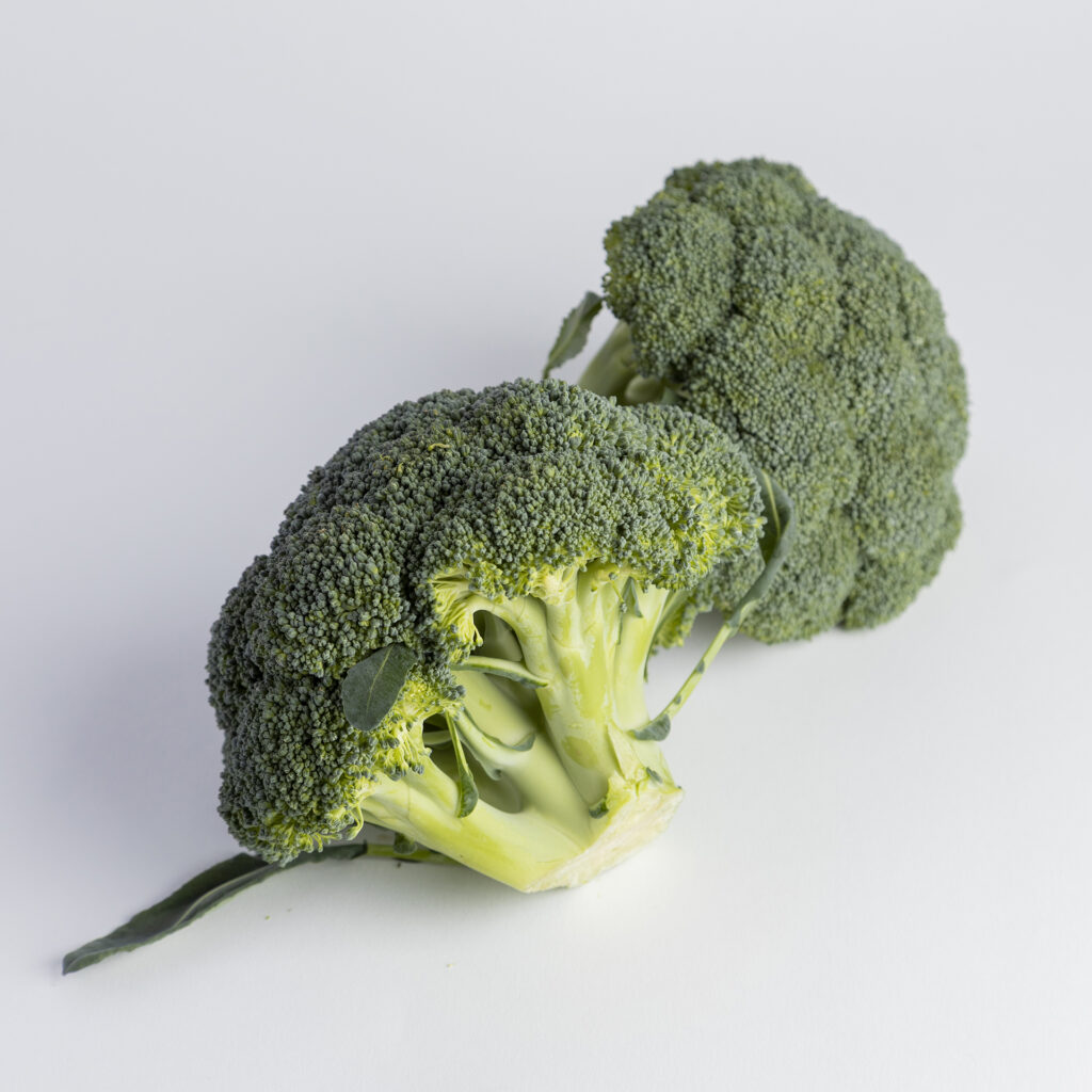 Fresh organic broccoli heads on a white background, showcasing crisp green florets and stems.