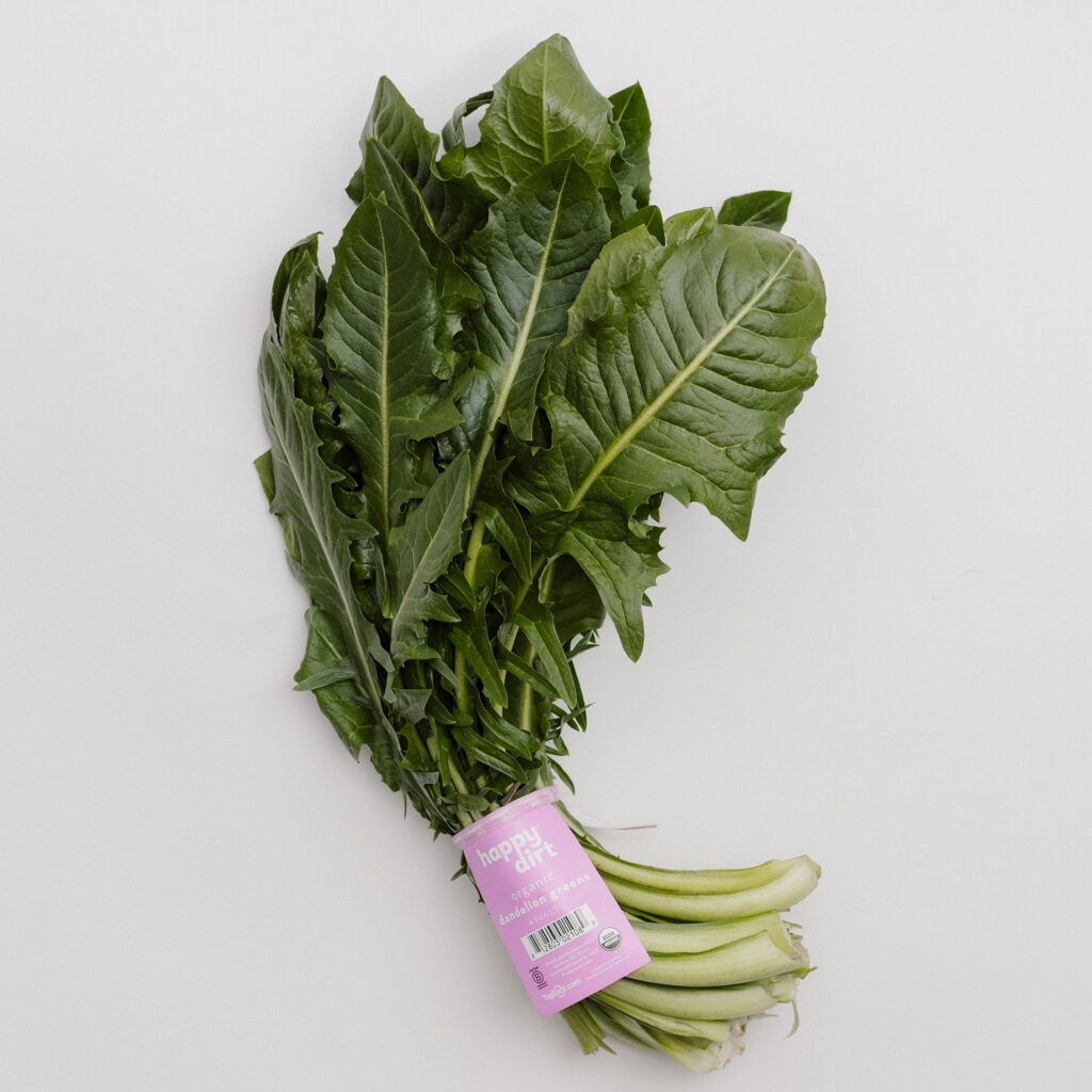 one bunch of dandelion greens with a pink happy dirt skirt tag, laying on a white surface.