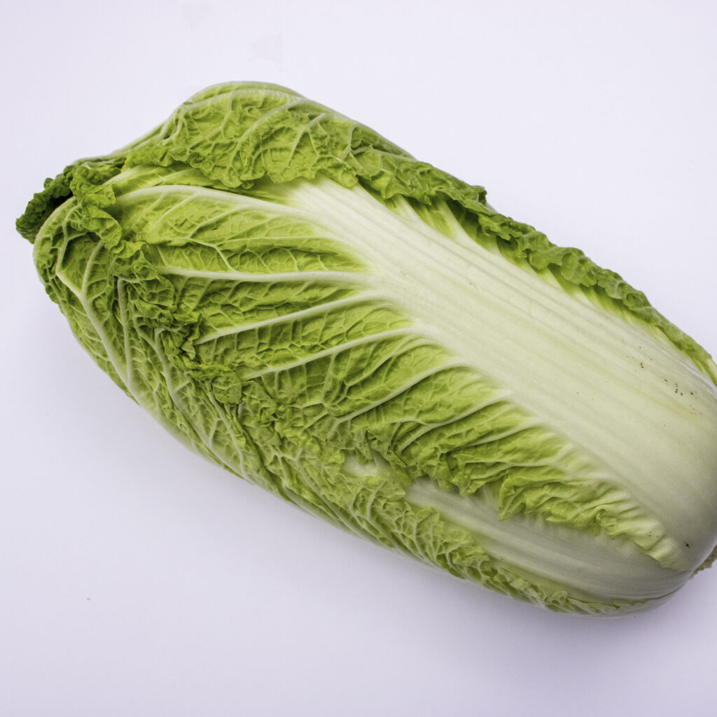 a head of organic napa cabbage on a white surface.