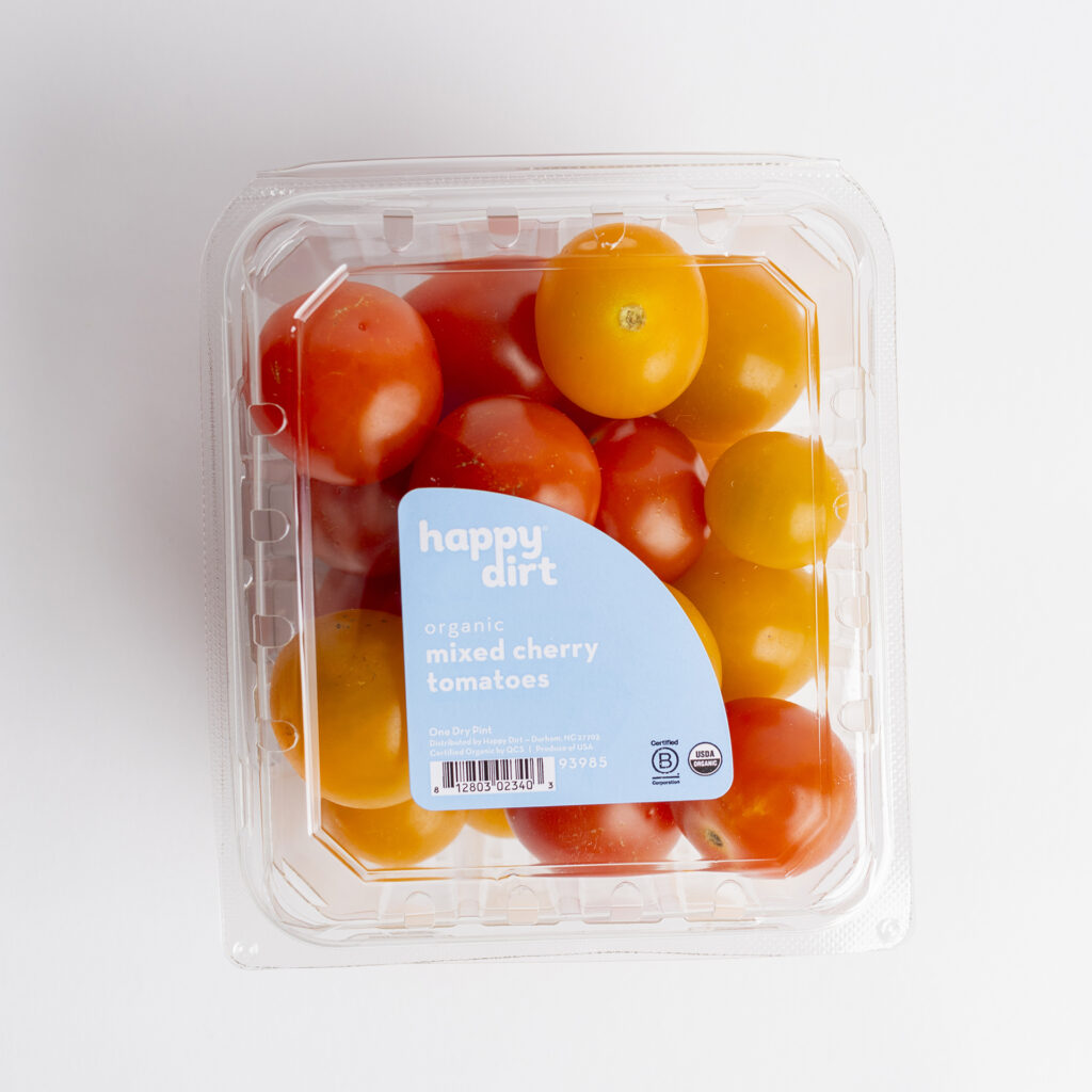 clamshell pint filled with organic mixed cherry tomatoes on a white surface